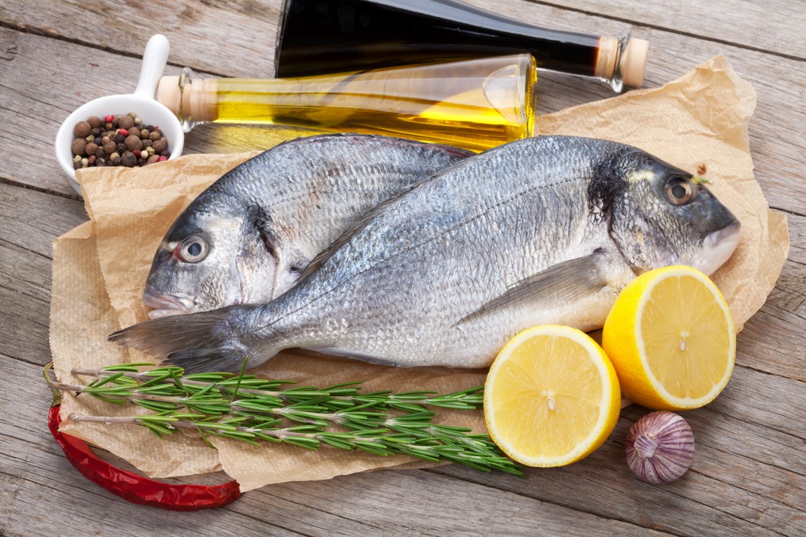 Fresh dorado fish cooking with spices and condiments on wooden table